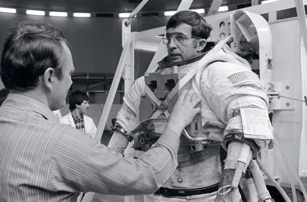 Buzos de apoyo acompañan a un astronauta sumergido mientras manipula un asidero de la maqueta