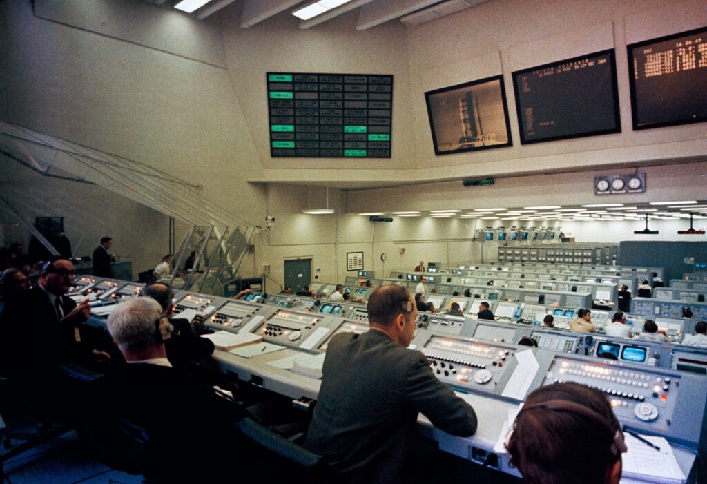 Sala de control de lanzamiento con filas de consolas y pantallas de seguimiento del vuelo
