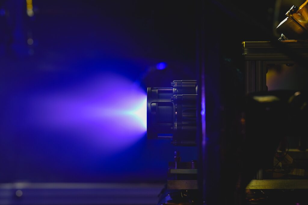 Propulsor de efecto Hall encendido en una cámara de vacío, con el penacho azulado característico