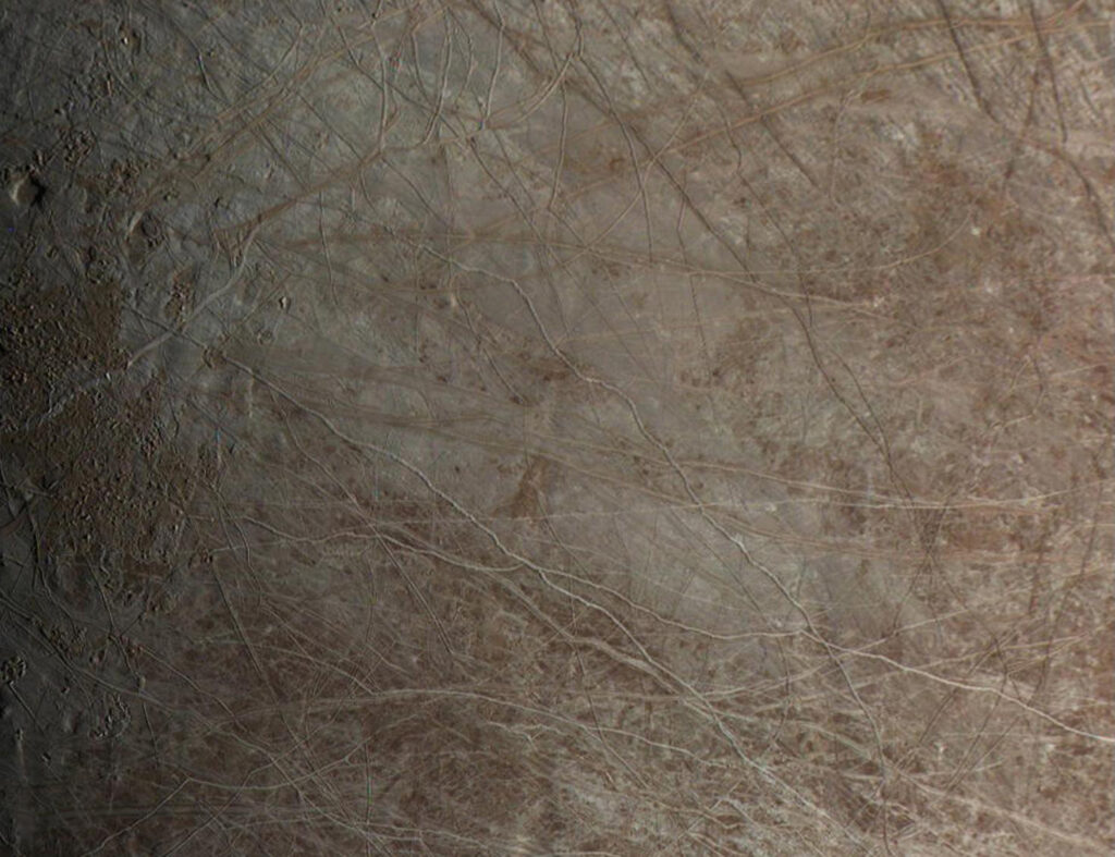 Superficie helada de Europa surcada por grietas oscuras que atraviesan el terreno de lado a lado