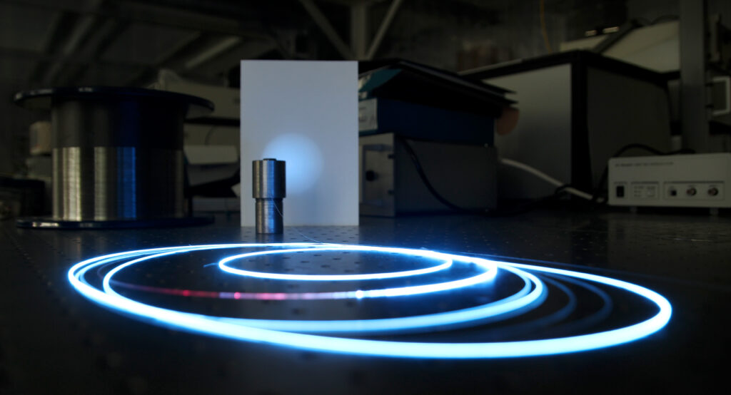 Bobina de fibra óptica transparente enrollada en un carrete de laboratorio bajo luz fría