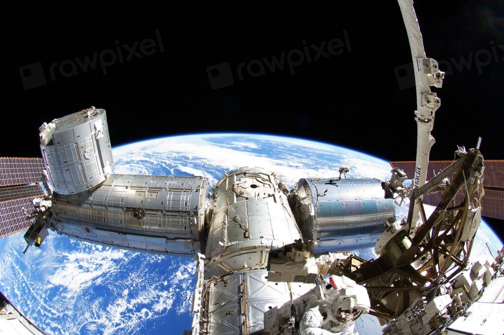 Astronauta sujeto al exterior de la estación durante una salida, con la Tierra al fondo