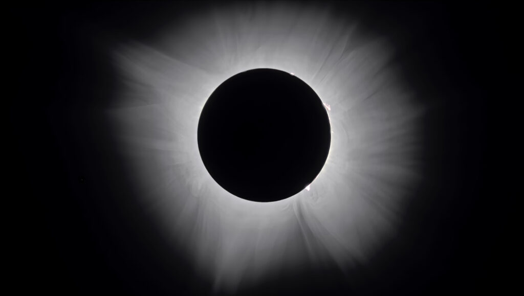 Corona solar extendida alrededor del disco oscurecido durante un eclipse total, con filamentos bien marcados