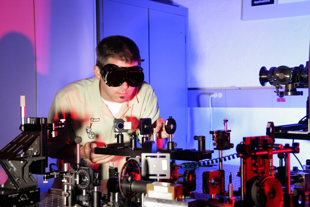 Mesa óptica de laboratorio con espejos y haces de láser alineados sobre una superficie antivibración