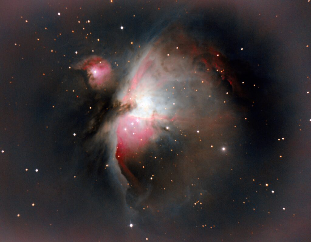 Nebulosa de emisión con filamentos rojizos y un cúmulo de estrellas jóvenes en su parte central